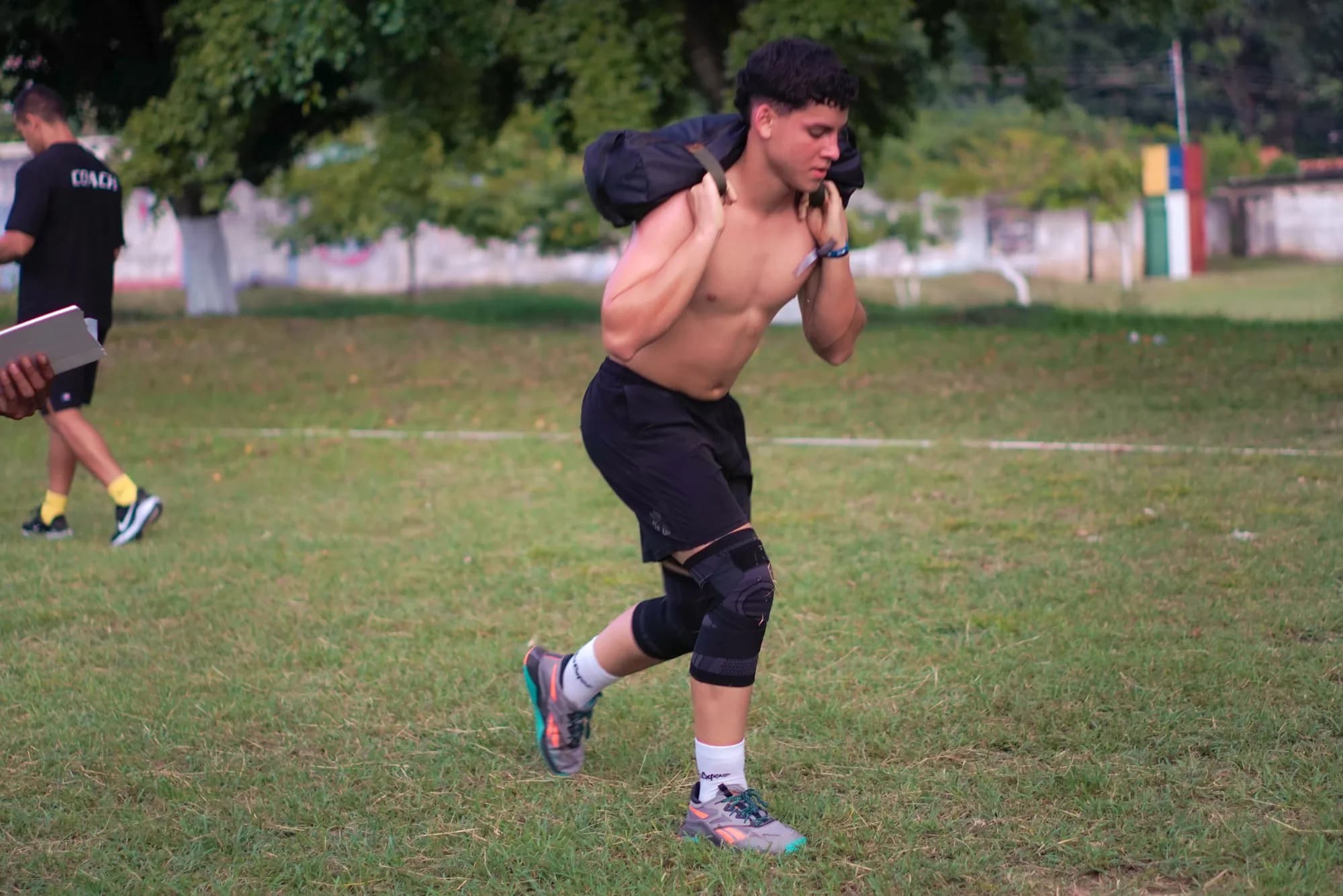 Un participante corre cargando un saco de arena sobre los hombros durante el FitClub Fest.