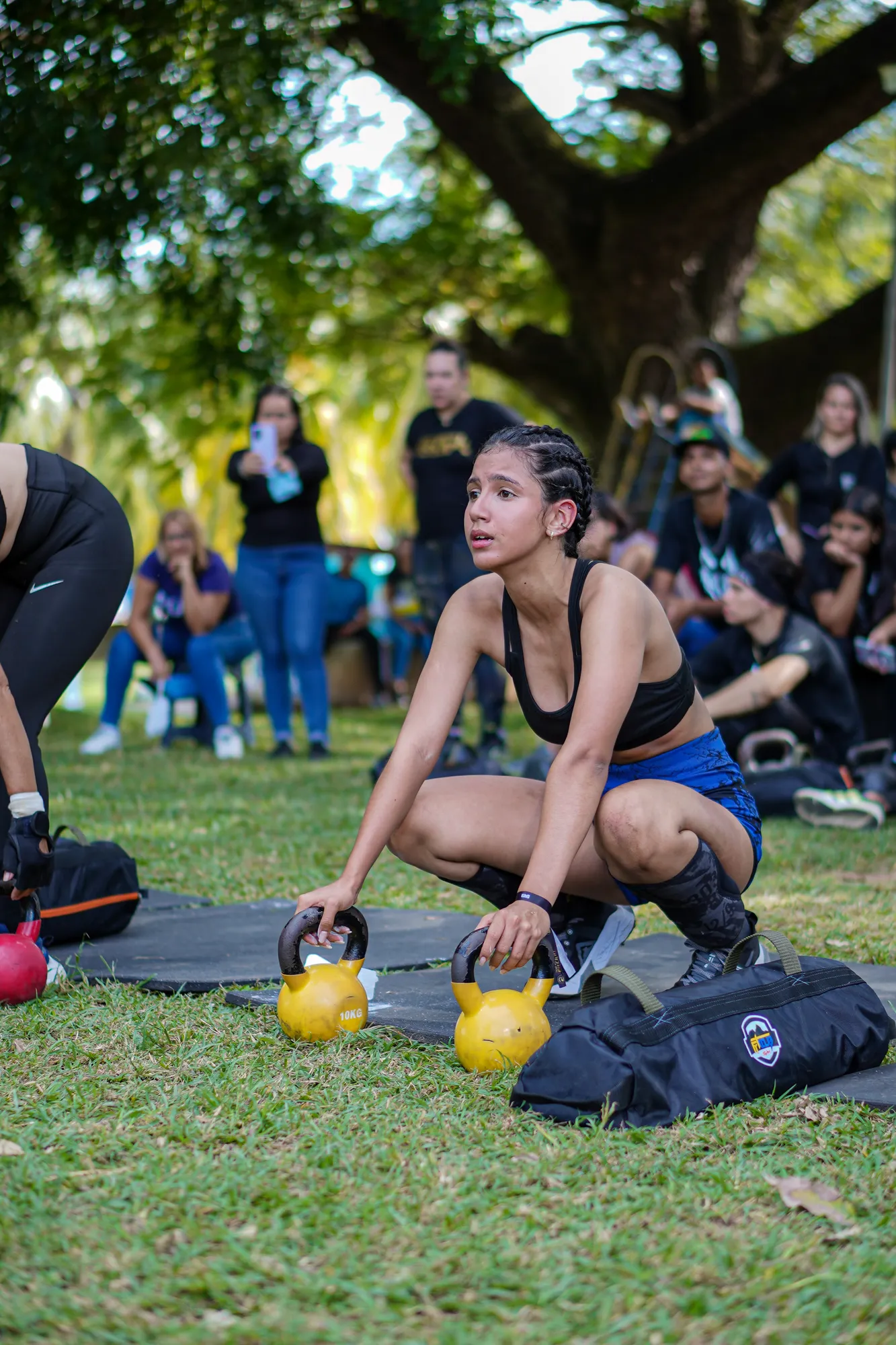Una participante toma dos pesas rusas en cuclillas durante una estación del FitClub Fest.